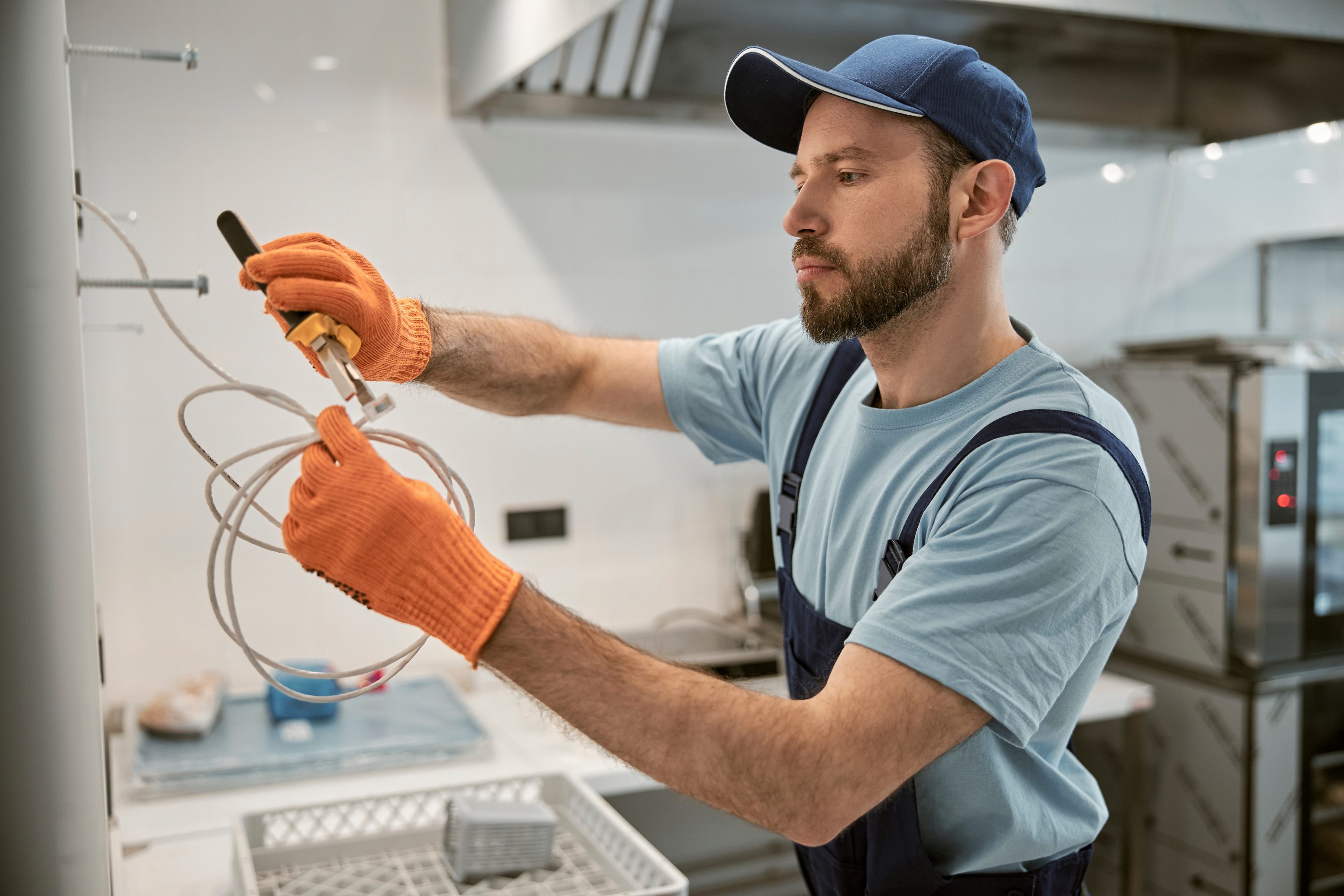 Um trabalhador efetuando a manutenção/instalação de cabos para cozinha industrial - Famatel Blog
